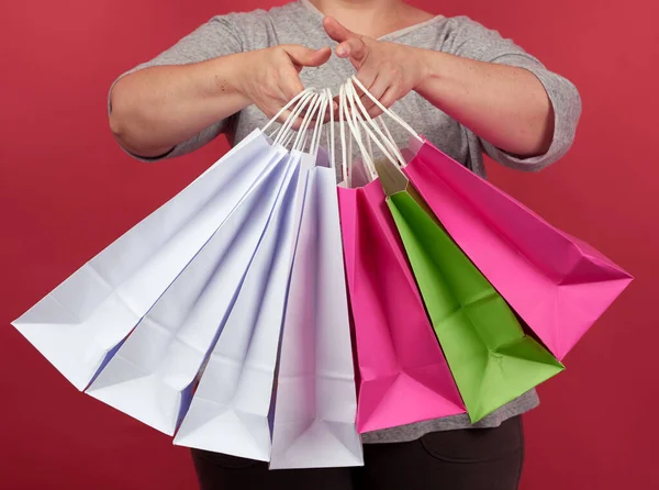 Mujer Sostiene Pila Bolsas Papel Sobre Fondo Rojo Concepto Compras — Foto de Stock