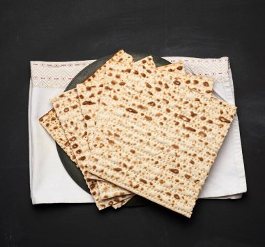 Siyah ahşap arka planda pişmiş kare matzo yığını.