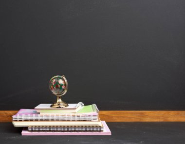 Kağıt okul defterleri ve siyah tebeşir tahtası arka planında cam küre yığını, boşluğu kopyala