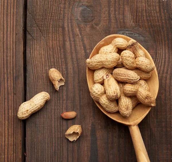 Masadaki tahta kaşıkta soyulmamış fıstık, lezzetli ve sağlıklı meyve, üst manzara.