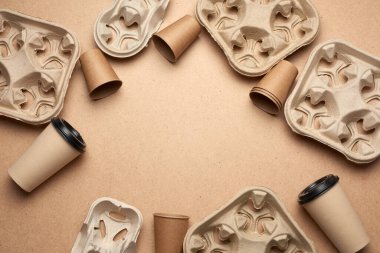 Kahverengi el işi kağıdından tek kullanımlık kağıt bardaklar ve kahverengi ahşap arka planda geri dönüştürülmüş kağıt tutucular, üst görünüm, yazılar için yer. Plastik reddetme konsepti, sıfır atık 