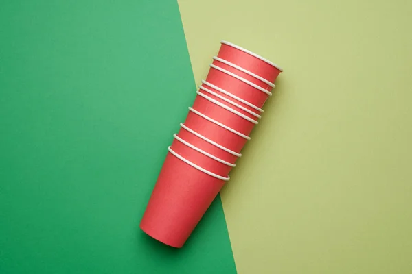 绿色底座上堆放红纸一次性杯子 概念环保 零浪费 — 图库照片