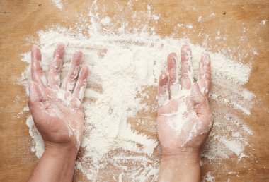 iki el ve beyaz buğday unu kahverengi ahşap bir zemine saçılmış, ürün yüzeye yayılmış, mutfak arka planı, üst görünüm