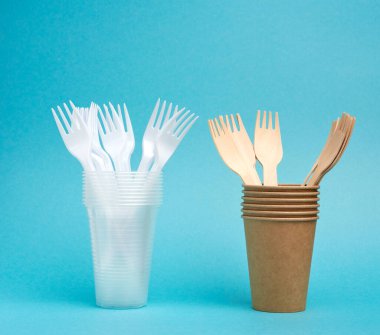 Tek kullanımlık sofra takımından bozunmaz plastik bardaklar ve çatal ve mavi arka planda, çevresel geri dönüşümlü malzemelerden bir set tabak. Plastik ve çevre koruma kavramlarının reddedilmesi