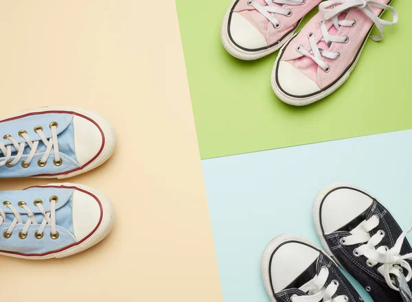 multi-colored well-worn textile sneakers of different sizes on a green background, top view, concept, family and team, friendship, copy space