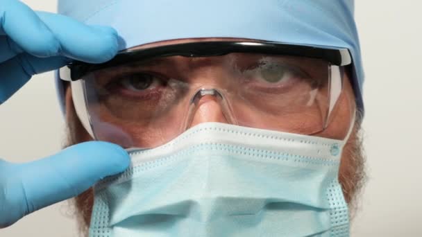 Γιατρός Πλαστικά Διάφανα Γυαλιά Προστατευτική Ιατρική Μάσκα Και Μπλε Υφασμάτινο — Αρχείο Βίντεο