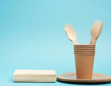 Kağıt bardak, kahverengi kağıt tabaklar ve ahşap çatallar ve mavi arka planda bıçaklar. Plastik reddetme konsepti, sıfır atık 