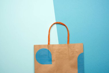 Mavi arka planda alışveriş için sapları olan kahverengi kağıt çanta, düz yatak, çevreyi kurtarmak için plastik torbaların reddedilmesi konsepti, üst görünüm
