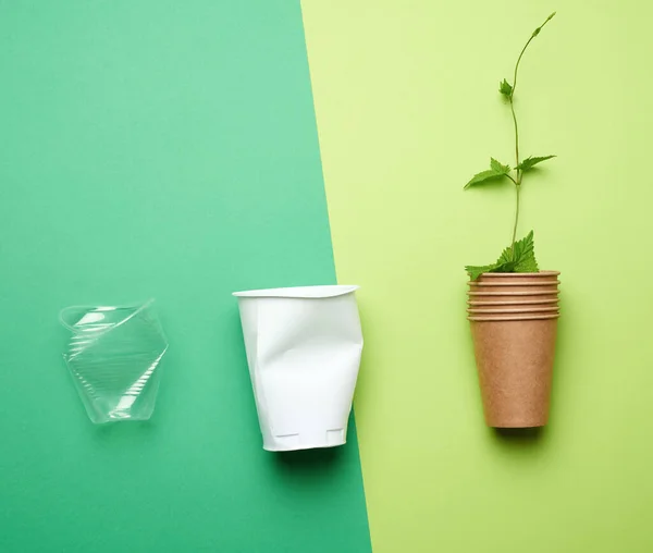 Műanyag Poharak Papír Pohár Ággal Zöld Levelek Zöld Háttér Környezetszennyezés — Stock Fotó