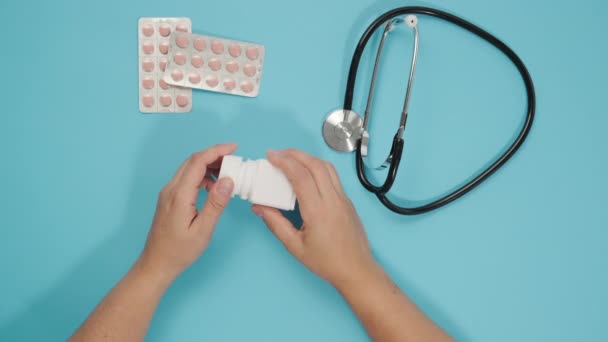 Mano Femenina Verter Píldoras Botella Plástico Blanco Sobre Fondo Azul — Vídeos de Stock