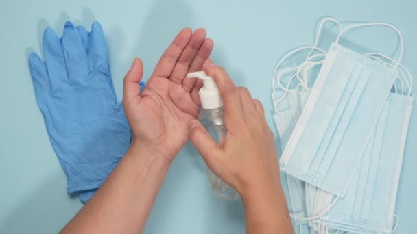 Žena Dezinfikuje Ruce Antiseptickou Pěnou Přes Modré Pozadí Jednorázovými Maskami — Stock video