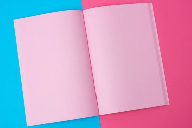 Mavi arkaplan üzerinde boş pembe sayfaları olan açık bir defter, üst görünüm, düz uzanma
