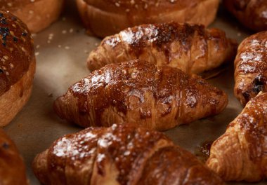 Kahverengi parşömen kağıdında pişmiş kruvasan. Lezzetli ve iştah açıcı hamur işleri.