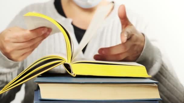 Woman Gray Clothes Medical Mask Sits Stack Books Turns Pages — Stock Video