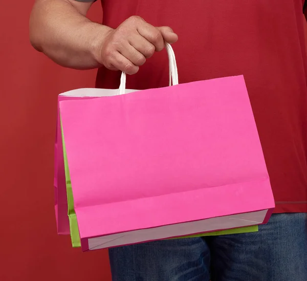 Man Red Clothes Holds Stack White Paper Bags Red Background — Stock Photo, Image