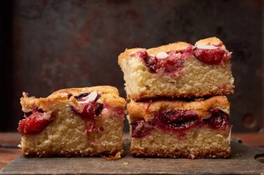 Kare şeklinde sünger kek dilimleri ahşap mutfak tahtasının üzerinde, kapat.