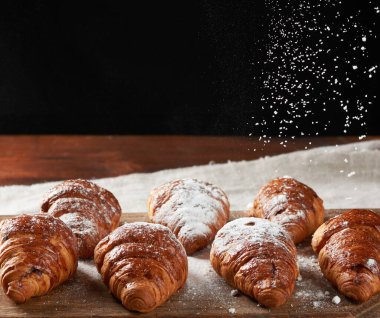 Tahtaya pudra şekeri serpiştirilmiş kruvasanlar, yukarıdan gelen şeker