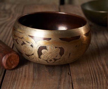 Kahverengi ahşap masa üzerinde ahşap bir çırpıcıyla Tibet 'te şarkı söyleyen bakır kâse meditasyon ve alternatif tıp aletleri.