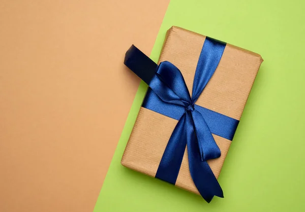 長方形の箱が茶色の紙に包まれ 弓で絹のリボンで結ばれ 緑の背景に贈り物 トップビュー コピースペース — ストック写真