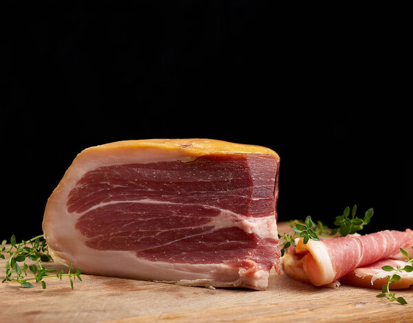 нарезанный на куски прошутто на коричневой деревянной доске, крупным планом