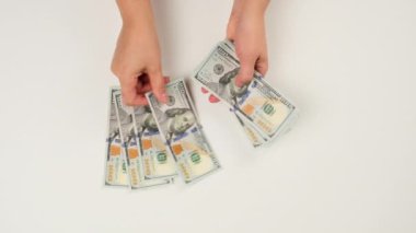 Kadın eli beyaz yüzeyde 100 dolarlık banknotlar düzenler.