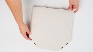 Masaya iki kadın eli koy. Üstünde pizza, teslimat konsepti ve üst görünüm olan beyaz bir karton kutu.