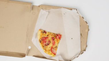 Beyaz bir masanın üzerindeki karton kutuda bir pizza parçası. Erkek ve kadın eli yiyecekleri kendilerine çekiyor.