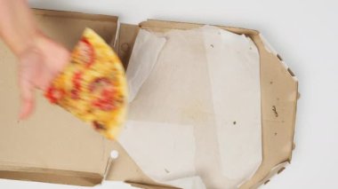 Kadın eli, erkeğe üzerinde sosis olan lezzetli bir dilim pizza verir. Kağıt kutu, beyaz masa, üst manzara.