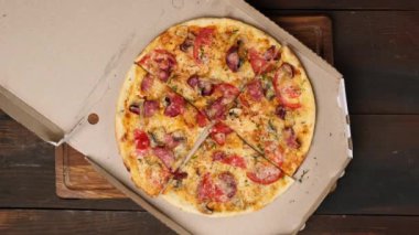 Peynirli, domatesli, sosisli ve mantarlı fırında pizza beyaz bir karton kutuda parçalara ayrıldı.