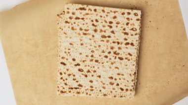 İki kadın el, kahverengi parşömen kağıdının üzerine kare bir matza koyar. Seder 'in bayramlık Paskalya yemeği için.