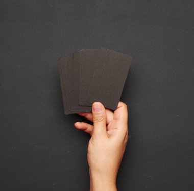 Kadın eli boş bir siyah kartvizit destesini boş bir kara tebeşir tahtasında tutuyor.