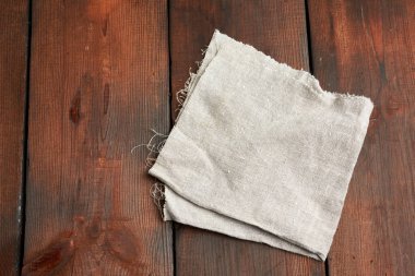 Gri mutfak tekstil havlusu eski tahtalardan, üst manzaradan, boş alandan kahverengi ahşap bir masaya katlanmış. Kırsal doku. Retro arkaplan