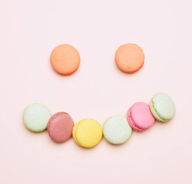 fırında çok renkli badem kurabiyeleri bej arka planda sıralanmış, figür gülüşü