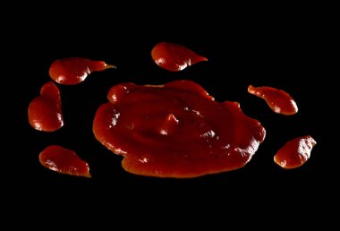 Dökülmüş domates ketçapı ve siyah arka planda izole edilmiş baharatlar.