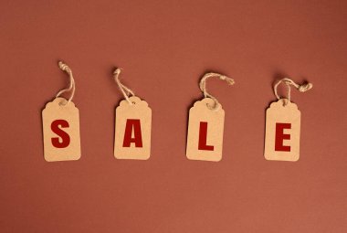 Kahverengi arka planda yazı indirimi olan kahverengi kağıt etiketler, mevsimsel indirim kavramı, üst görünüm