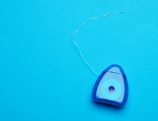 Niebieskie Plastikowe Opakowanie Nitką Dentystyczną Niebieskim Tle Zbliżenie Widok Góry — Zdjęcie stockowe