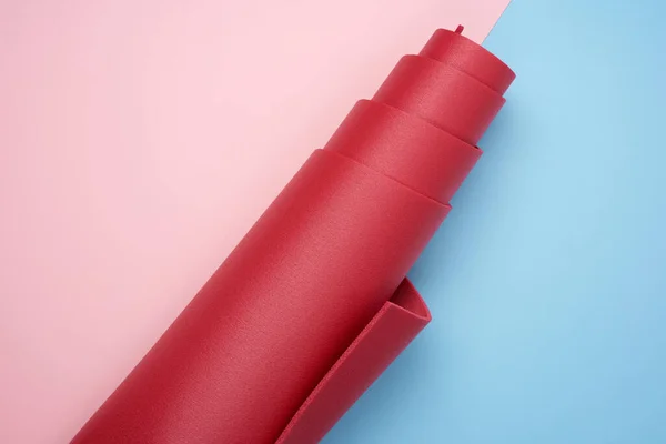 粉色蓝色背景下用于瑜伽和运动的扭曲红色氯丁烷垫 — 图库照片