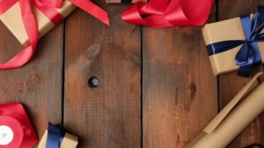 Kahverengi kraft kağıdına doldurulmuş hediyeler. Kahverengi ahşap masaya ipek kurdele bağlanmış. Kadın elleri kutuyu ortaya koyuyor.