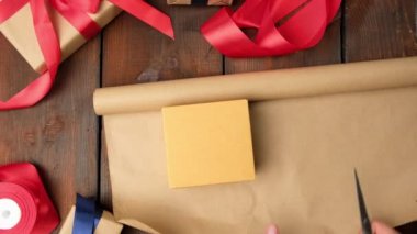Kutuları kahverengi kraft kağıdına sarma işlemi ahşap bir masa, bayram hediyeleri, üst manzara
