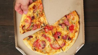 Beyaz bir karton kutuda sosisli, domatesli ve peynirli fırında pizza.