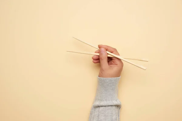 Ζεύγος Ξύλινων Chopsticks Γυναικείο Χέρι Μπεζ Φόντο Κοντινό — Φωτογραφία Αρχείου