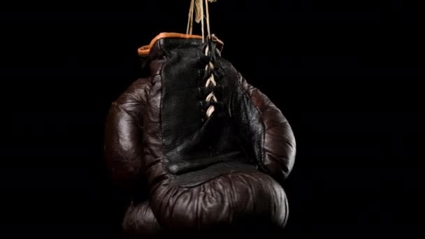 黒の背景にぶら下がっている革のヴィンテージブラウンのボクシンググローブのペアを閉じます — ストック動画