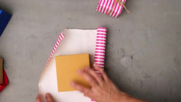 グレーのテーブルにピンクの紙に茶色の四角形の箱を詰め女性 フルーツパッキングプロセス トップビュー — ストック動画