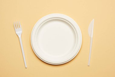 Bej arka planda, geri dönüştürülmüş malzemelerden yapılmış boş kahverengi tek kullanımlık tabak. Geri dönüşümsüz çöp yokluğu kavramı, plastiğin reddi