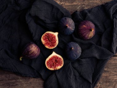 Siyah bir peçetenin üzerinde, bütün ve yarı yarıya mor incirler, üst manzara.