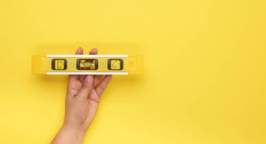 Kadınlar sarı arka planda kapsülleri olan plastik sarı seviyeli el tutuşu aracı, boşluğu kopyala