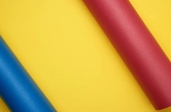 黄色背景下用于瑜伽和运动的红色和蓝色折叠床 — 图库照片