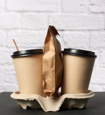 Tepside plastik kapaklı iki adet tek kullanımlık kahve bardağı, beyaz arka plan, paket servis kutuları.