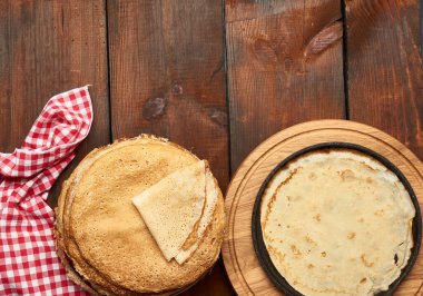 Ahşap bir tahtaya, kahverengi masaya, üst manzaraya dizilmiş ince, fırınlanmış gözlemeler.