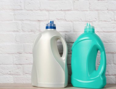 Beyaz tuğlalı arka planda sıvı deterjanı olan iki büyük plastik şişe.